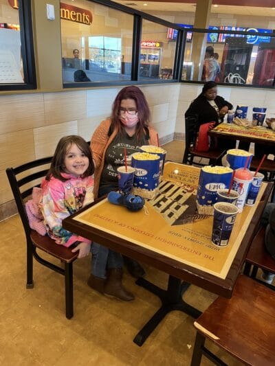 girl eating with her mom in the movie theater