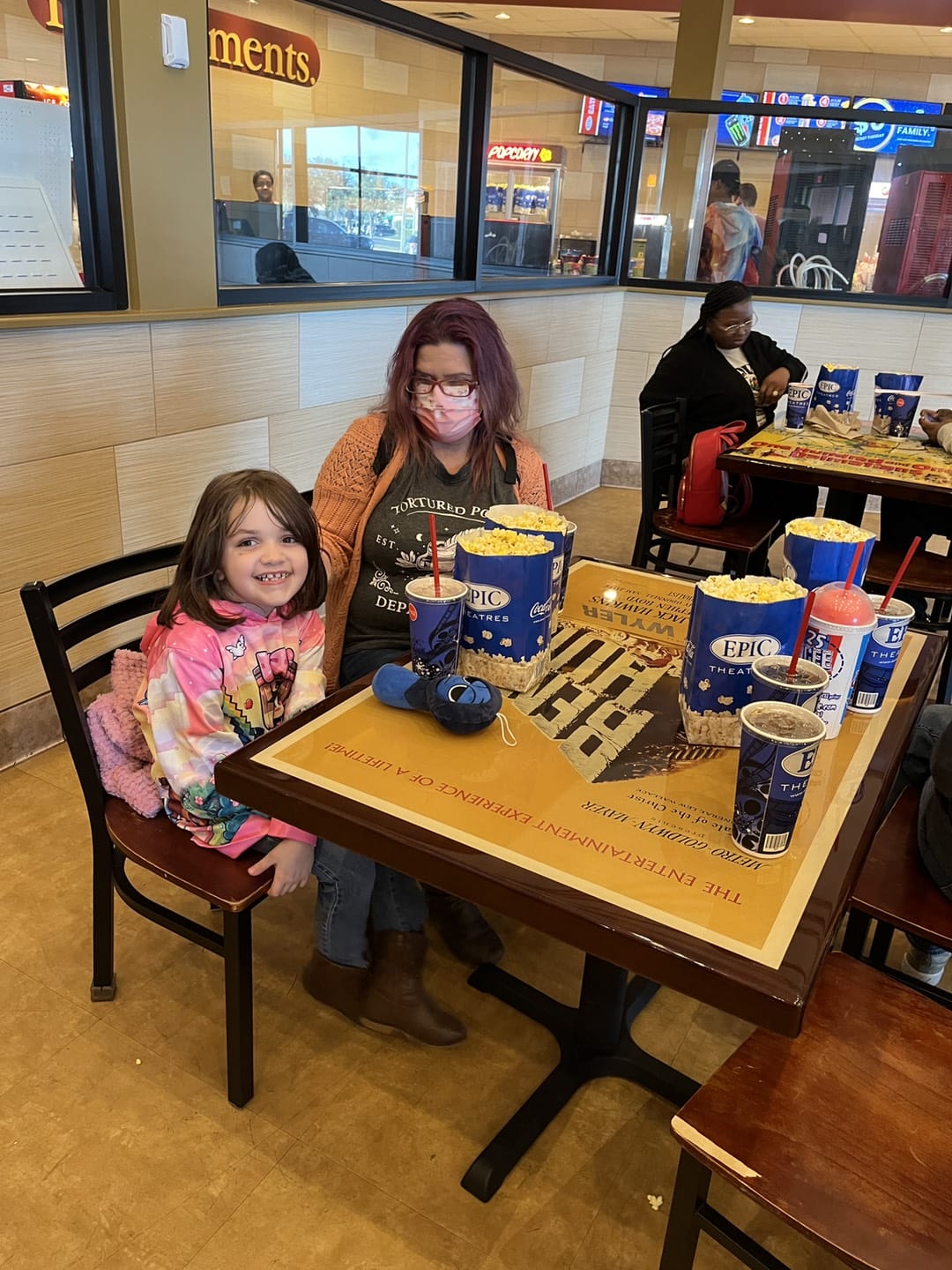 girl eating with her mom in the movie theater